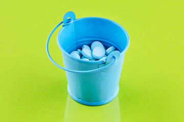 Fototapeta na wymiar Blue metal bucket with pills on green background