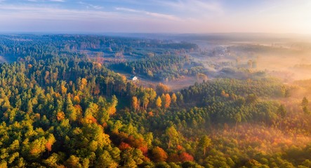 Aerial landscape with house and foggy sunrise over meadows and forest