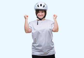 Young adult cyclist woman with down syndrome wearing safety helmet over isolated background celebrating surprised and amazed for success with arms raised and open eyes. Winner concept.