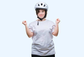 Young adult cyclist woman with down syndrome wearing safety helmet over isolated background celebrating mad and crazy for success with arms raised and closed eyes screaming excited. Winner concept