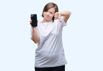 Young adult woman with down syndrome showing smartphone screen over isolated background with angry face, negative sign showing dislike with thumbs down, rejection concept