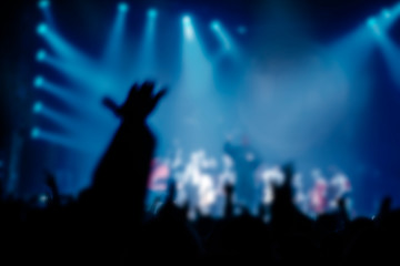 Fototapeta na wymiar Musical concert. People in the concert hall at the disco . Singer in front of the audience. Fans at the concert. Blurred image / blurred photo.