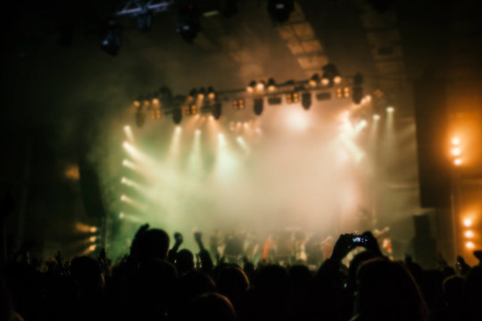 Musical concert. People in the concert hall at the disco . Singer in front of the audience. Fans at the concert. Blurred image / blurred photo.