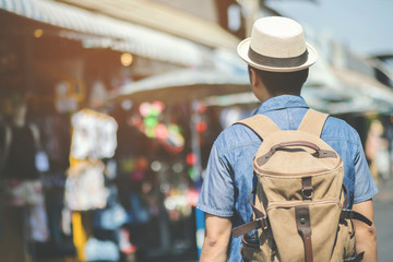 Young asian man traveler traveling backpacker walking in a famous street market in among the many people in asia. filler Vintage Tone and Selective Soft Focus.