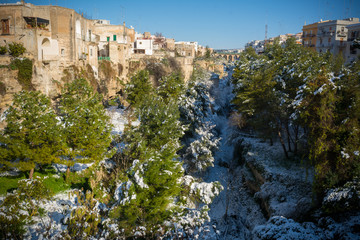 Fototapeta na wymiar Horizontal View of the Gravina of the Town of Massafra, Covered by Snow on Blue Sky Background
