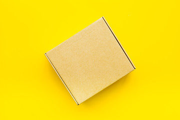 Delivery concept. Cardboard box on yellow background top view mockup