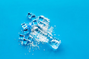 pile of ice cubes and plastic bottle on blue bar table top view mock-up