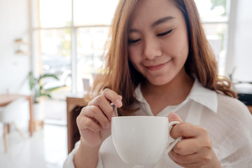 A beautiful Asian woman holding and drinking hot coffee with feeling good in cafe