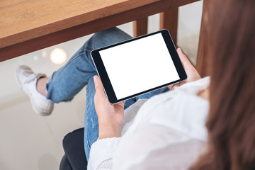 Top view mockup image of a woman holding black tablet pc with blank white screen horizontally while sitting on a chair