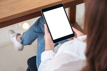 Top view mockup image of a woman holding black tablet pc with blank white screen while sitting on a chair