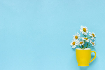 Bouquet chamomile daisies flowers in yellow mug on pastel blue color paper background Copy space Template for postcard, lettering, text or your design Flat lay Top view Concept Hello summer
