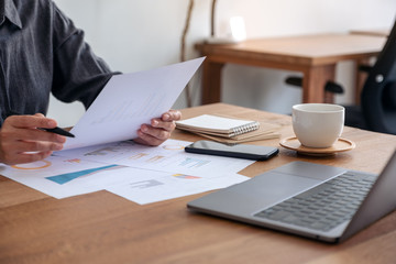 A businesswoman writing and working on business data and document with laptop on the table in office