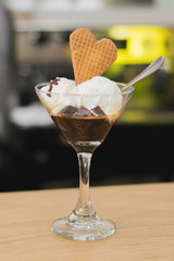 preparación de café con brownie y helado de vainilla con galleta en una una copa de cristal y cuchara   