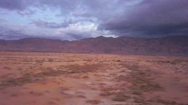 Flying over Edom Mountains Arava Rocky Desert. Israel Aerial Drone Of Middle Eastern Desert Convoy Tourism.Sand sandy desert and clouds. kibbutz in southern Israel