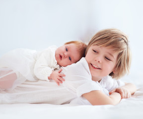 Fototapeta na wymiar newborn baby sister lying on cute elder brother