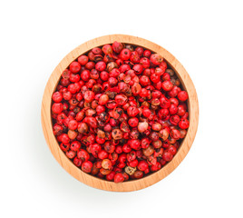 dried pink peppers in wood bowl on white background.