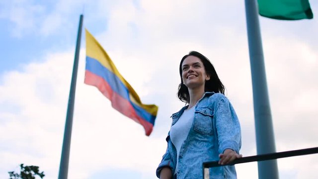 Happy girl smiling and posing in front of the Colombian flag in Medellin, Tourist Caucasian pretty girl smiling in front of the flag
