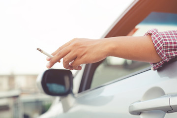 close up man hand smoking a cigarette in car. Cigarette smoke spread
