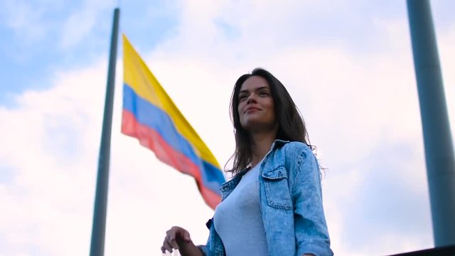 Slow motion of the beautiful young girl and Colombian flag in wind, Happy tourist young woman posing in front of national flag of Colombia