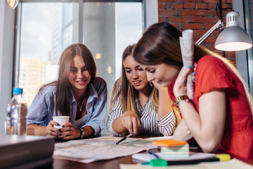 Three smiling female students learning together in classroom