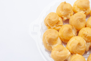 Profiteroles or Thai call Eclair in plastic box isolated on white background.