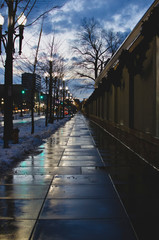 Obraz premium The wet sidewalk along the dim lit city street in salt lake. 