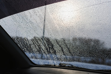 macro raindrops on warm blue car window/ spring/ summer weather background/ monsoon weather background 