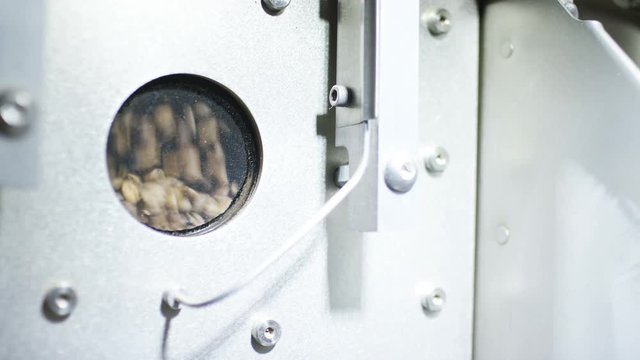 Coffee beans seen through a glass window being roasted in machinery in a roastery