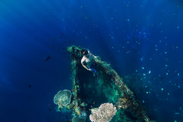 Freediver man dive at shipwreck, underwater
