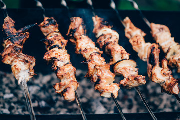 Grilled kebab cooking on metal skewer. Roasted meat cooked at barbecue. Traditional eastern dish, shish kebab. Grill on charcoal and flame, picnic, street food