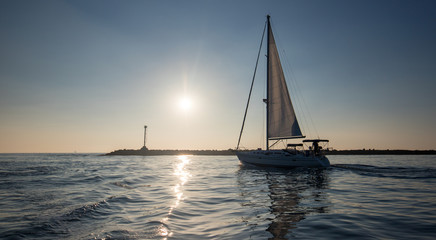 Fototapeta premium Sailboat going past jetty in the Channel Islands harbor in Oxnard California United States