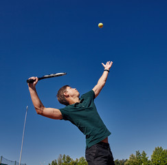 a Man playing tennis on the court on a beautiful sunny day