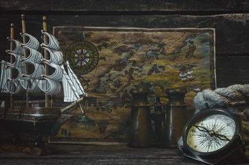 Pirate treasure map, compass, mooring rope and binoculars on a pirate captain table background.