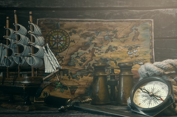 Pirate treasure map, compass, mooring rope, dagger and binoculars on a pirate captain table background.