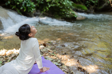 Beautiful girls are playing yoga at the park. Among the natural waterfalls in the forest, exercise concepts