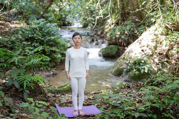 Beautiful girls are playing yoga at the park. Among the natural waterfalls in the forest, exercise concepts