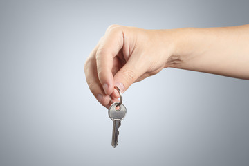 Hand holding a key on gray background