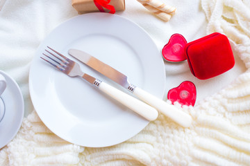  Romantic dinner on Valentine's Day with a box for a ring on a white background. Plate with fork and knife.