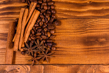 Pile of the coffee beans, star anise and cinnamon sticks on wooden table. Top view