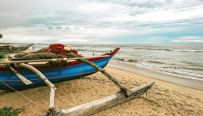 Traditional blue fishing boat on an empty and calm beach of Sri Lanka.
