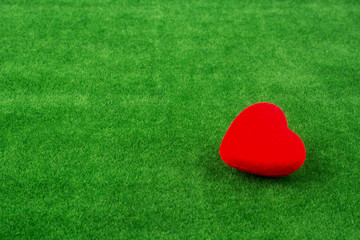 Red heart shape icon on grass