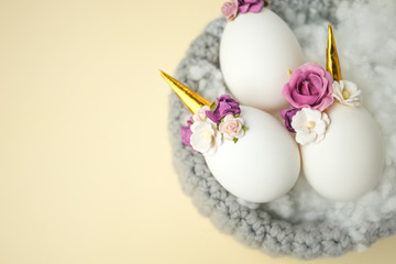 Obraz na płótnie Canvas Easter holiday concept with cute handmade eggs, unicorn and flower decoration in bird nest