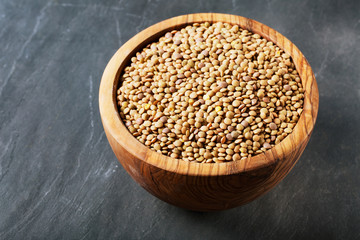 Dried lentils in a wooden bowl on a wooden table