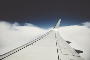 Airplane wing in flight seen through a window, color toning applied.