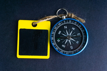 Wooden tag and compass on black background with selective focus and crop fragment. Business and motivation concept