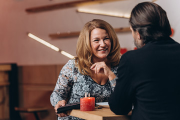 A middle-aged couple at a table in a cafe on Valentine's Day. Focus on a smiling blonde woman