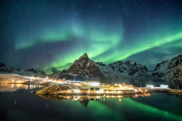 Poster Aurora borealis over mountains in scandinavian village glowing © Mumemories