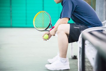 Sad tennis player sitting in the court after lose a match - people in sport tennis game concept