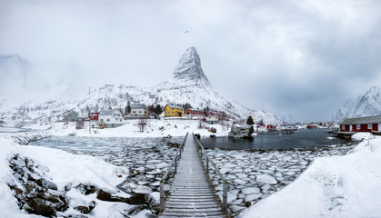 Panorama of fishing village in snow steep mountain with wooden bridge