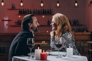 Man and woman are looking in love at each other while sitting at a table in a restaurant.